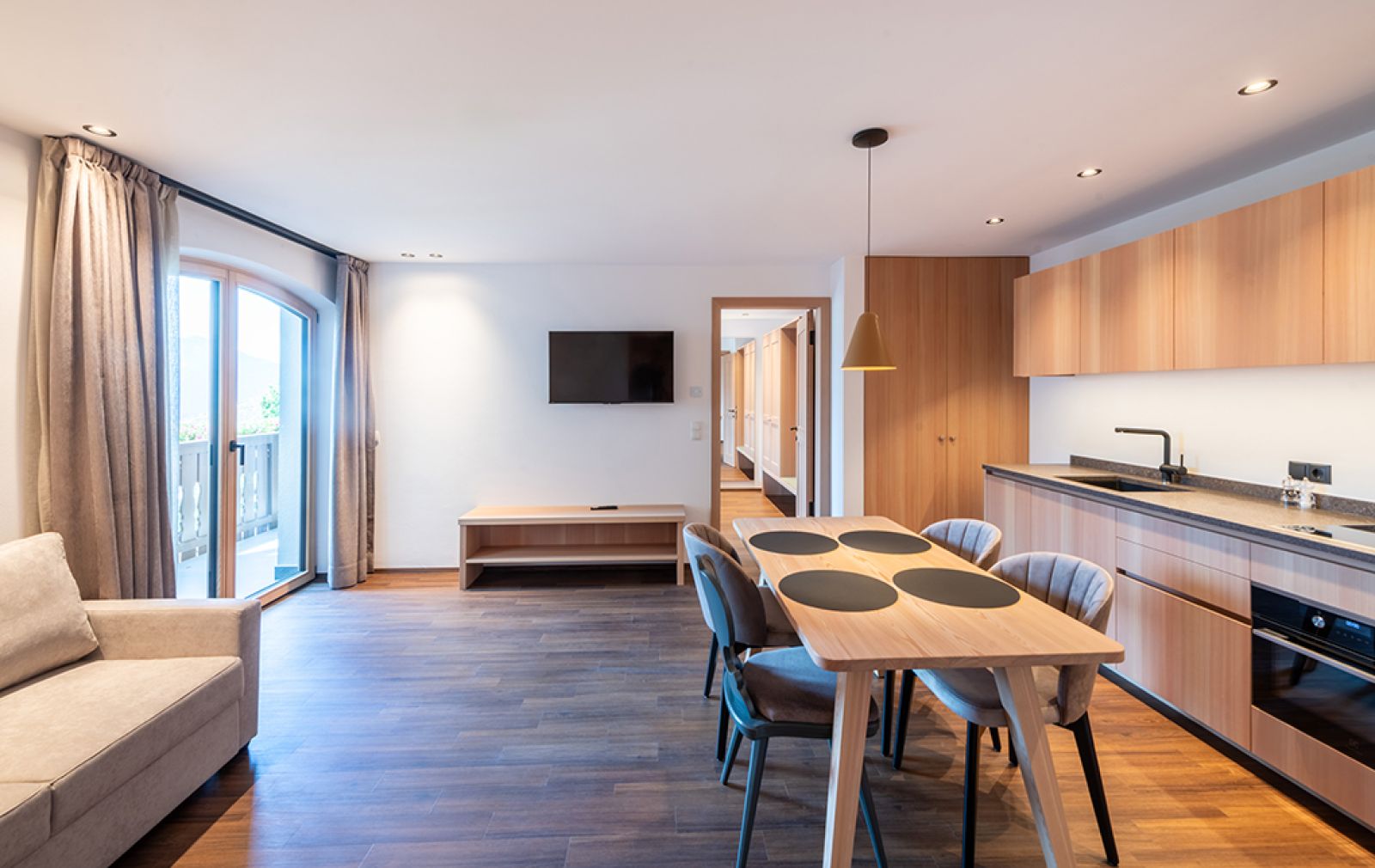 Modernes Appartement  in Truden: Heller Wohnbereich mit Sofa, Couchtisch, TV und offener Küche mit Esstisch