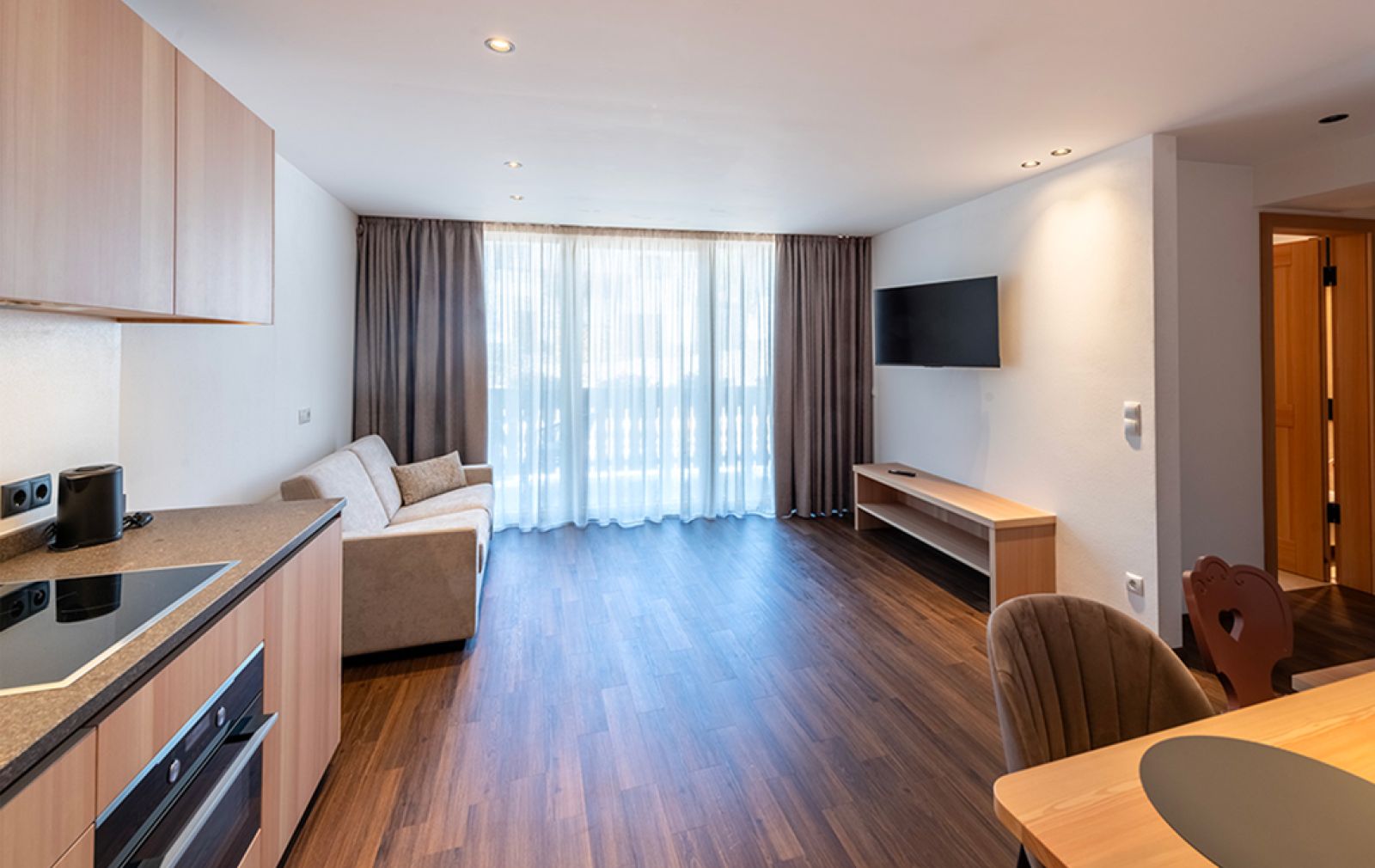 Modernes Appartement im Goldener Adler : heller Wohnbereich mit Küche, Esstisch, Sofa und Holzelementen