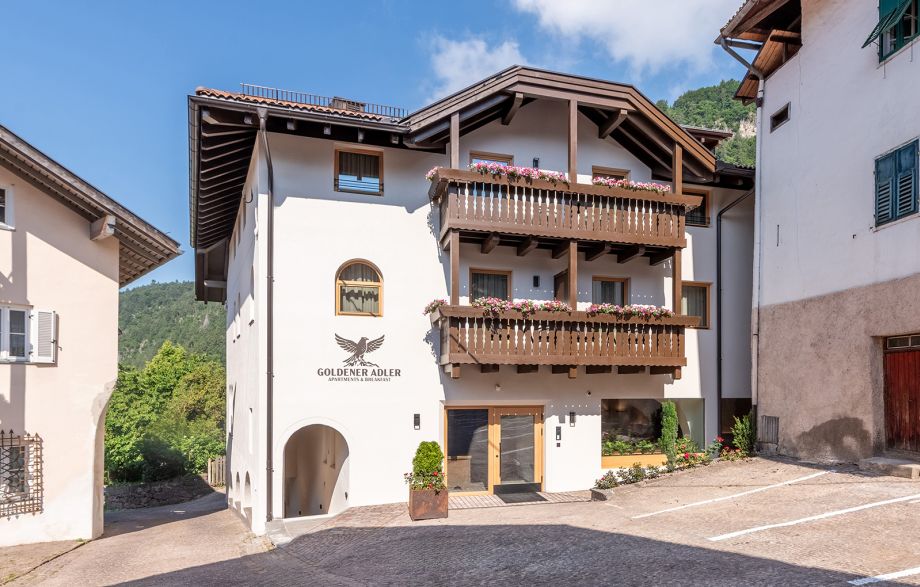 Vista esterna del Goldener Adler a Truden: un residence con balconi e architettura tradizionale nel Parco Naturale Monte Corno.
